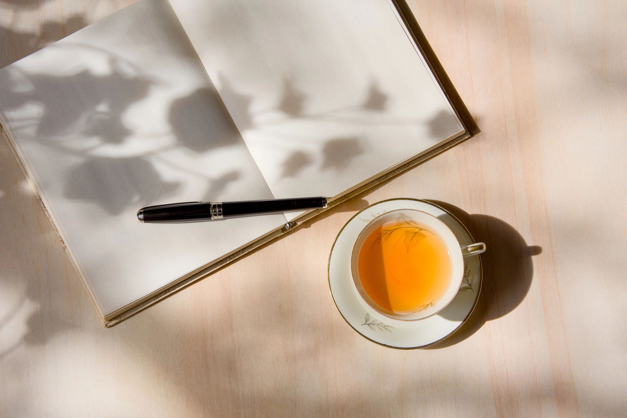 Tea in porcelain cup and journal on wooden table